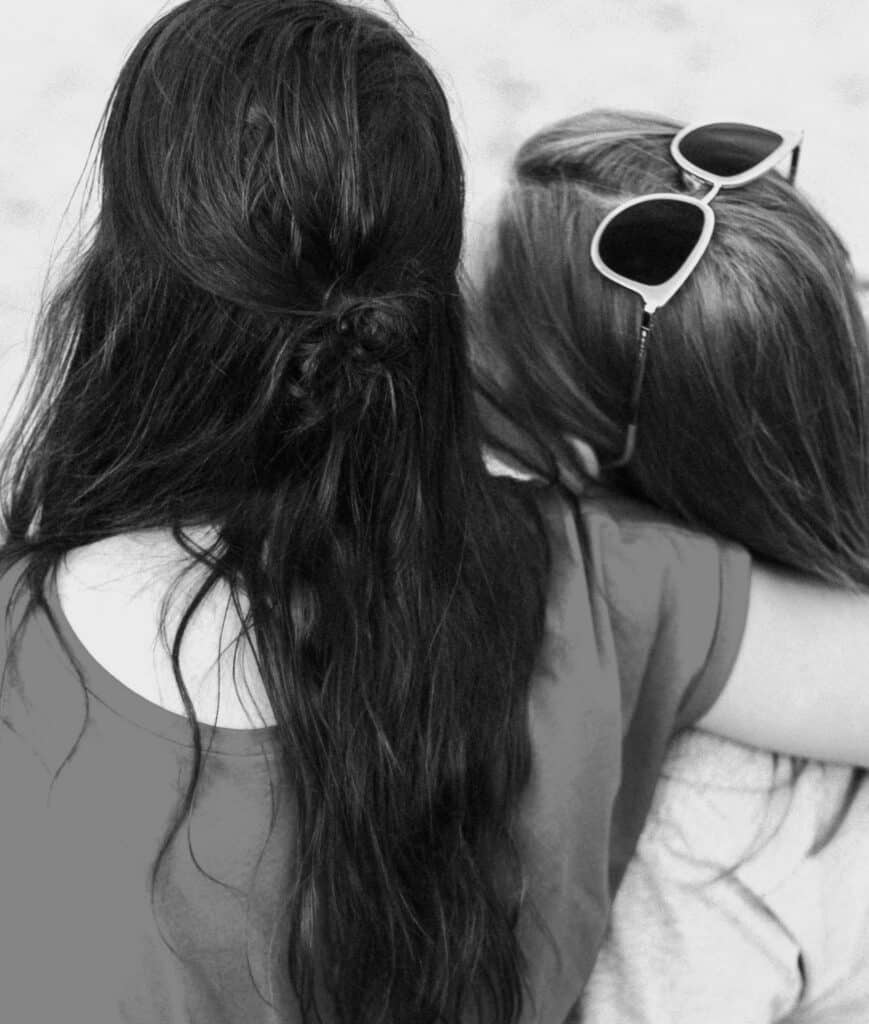 Sad woman comforting another woman with long hair, close-up of supportive emotional connection, mental health counselling, empathy, and compassion, black and white photo.