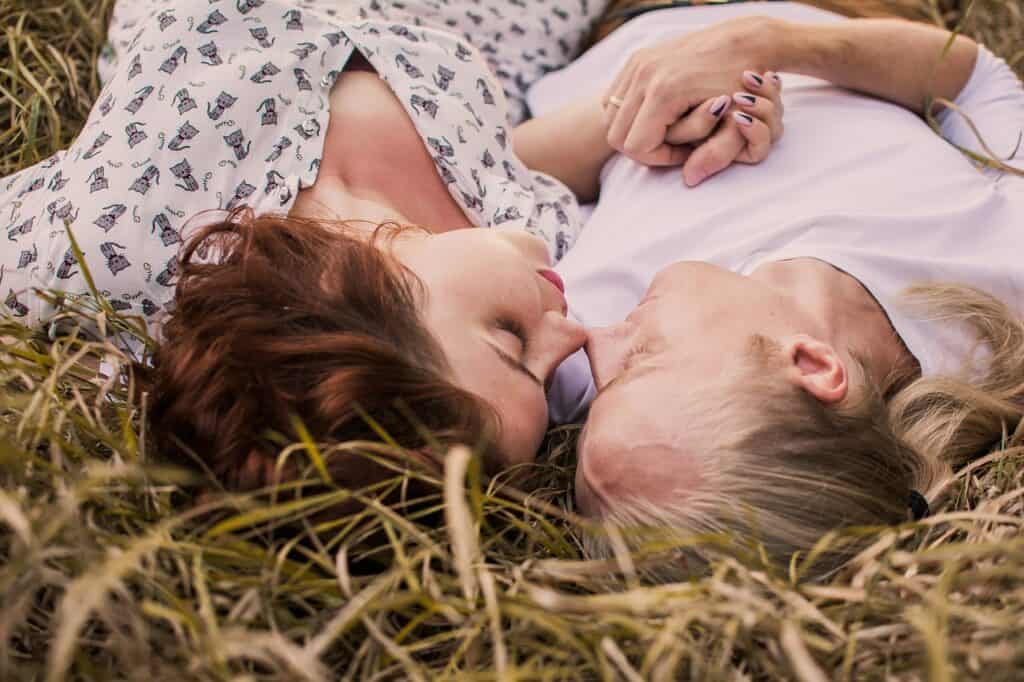 Soft focus image of two women lying on the grass, touching noses, expressing intimacy and emotional connection, symbolising love, trust, and emotional wellbeing in close relationships.