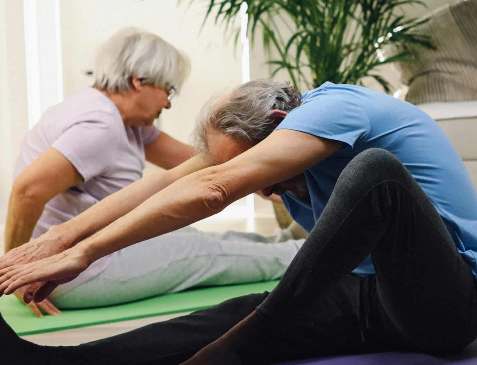 Older couple stretching together on mats, showing how Routine Relationship Boosters promote health and connection.