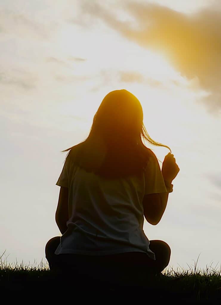 A woman reflects at sunset, symbolising emotional healing, Gratitude In Hard Times, and family remembrance.