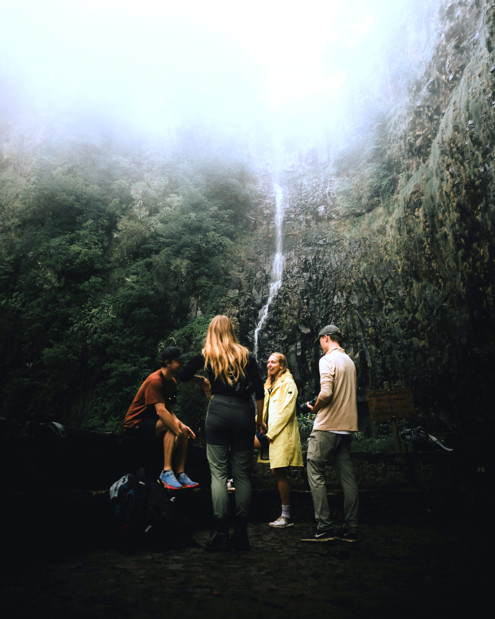 A group connects near a calming waterfall, showing how nature and movement support healing through Grateful Grounding In Motion.