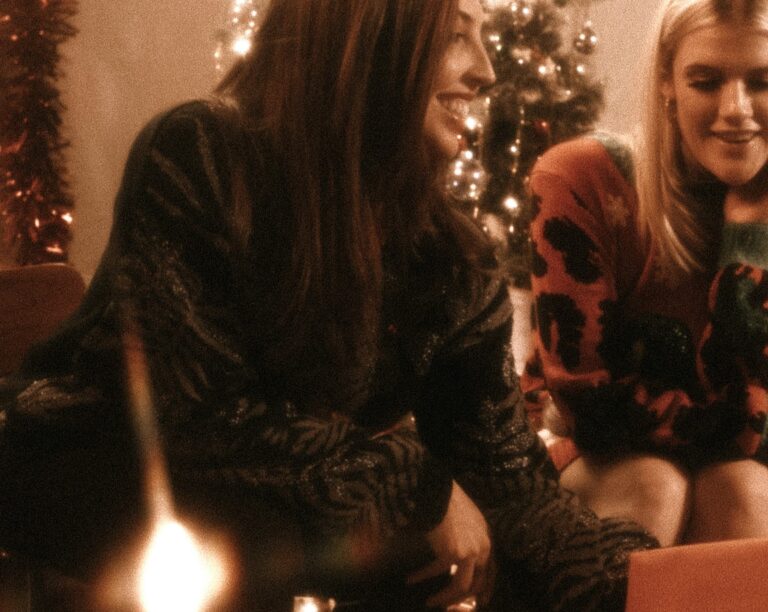 Two women share a warm Christmas moment, symbolising emotional connection through Joint Celebrations in blended families.