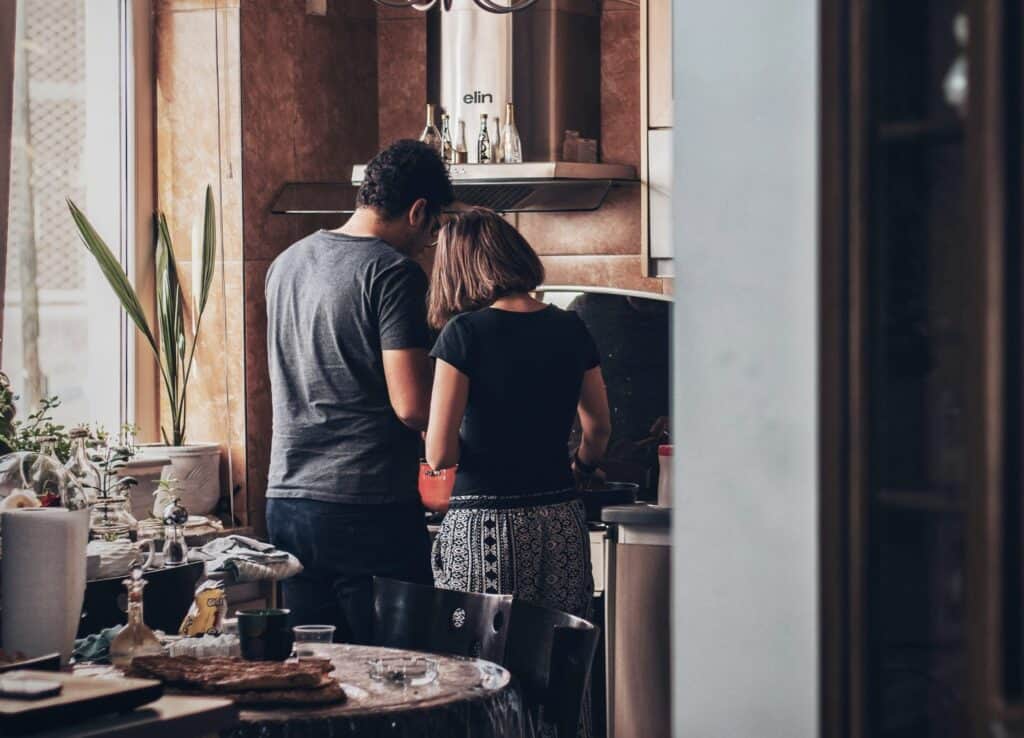 A couple cooks together in a cosy kitchen, sharing a moment of connection, teamwork, and routine Kitchen Bonding.