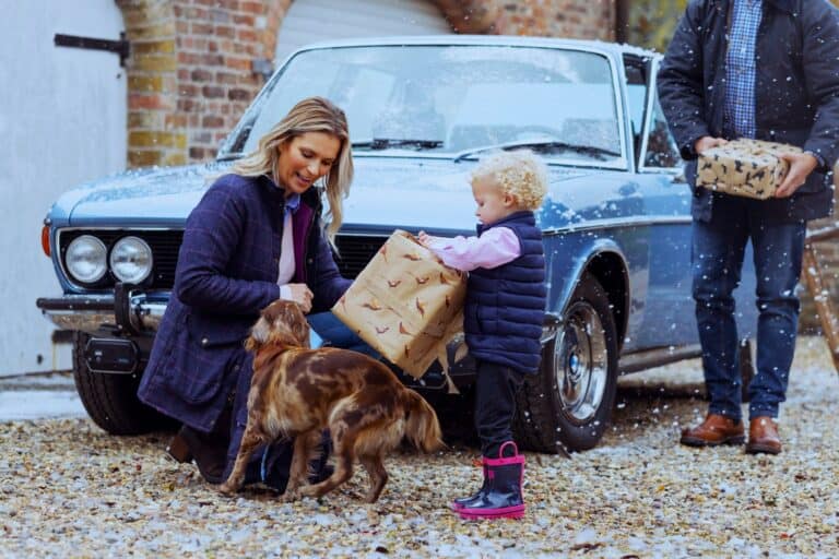 Co-parents and child share holiday gifts peacefully in snow, showing emotional unity even When Parenting Becomes Difficult.