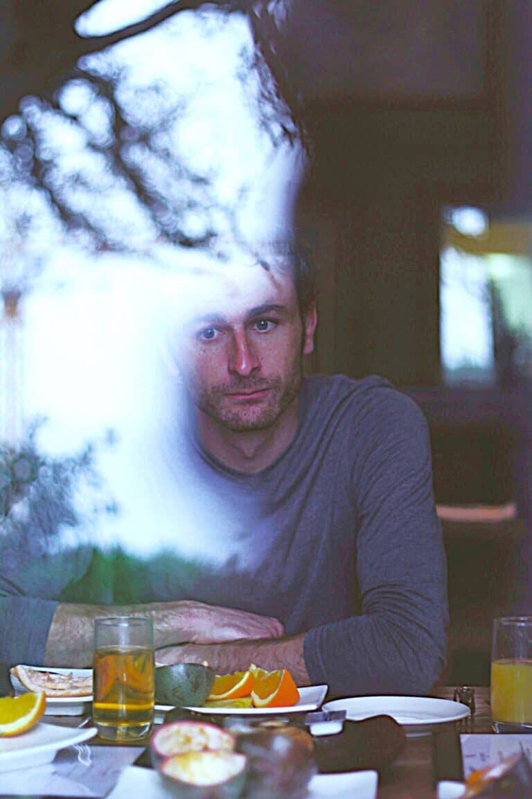 Zooming in on a man’s pained reflection through glass, his distant stare reveals Lingering Emotional Wounds.