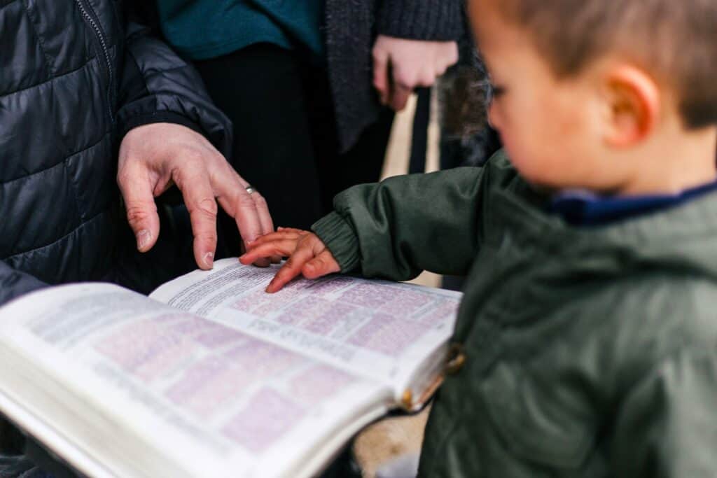 Adult guiding child’s hand while reading, showing how connection patterns form in the Family Environment.