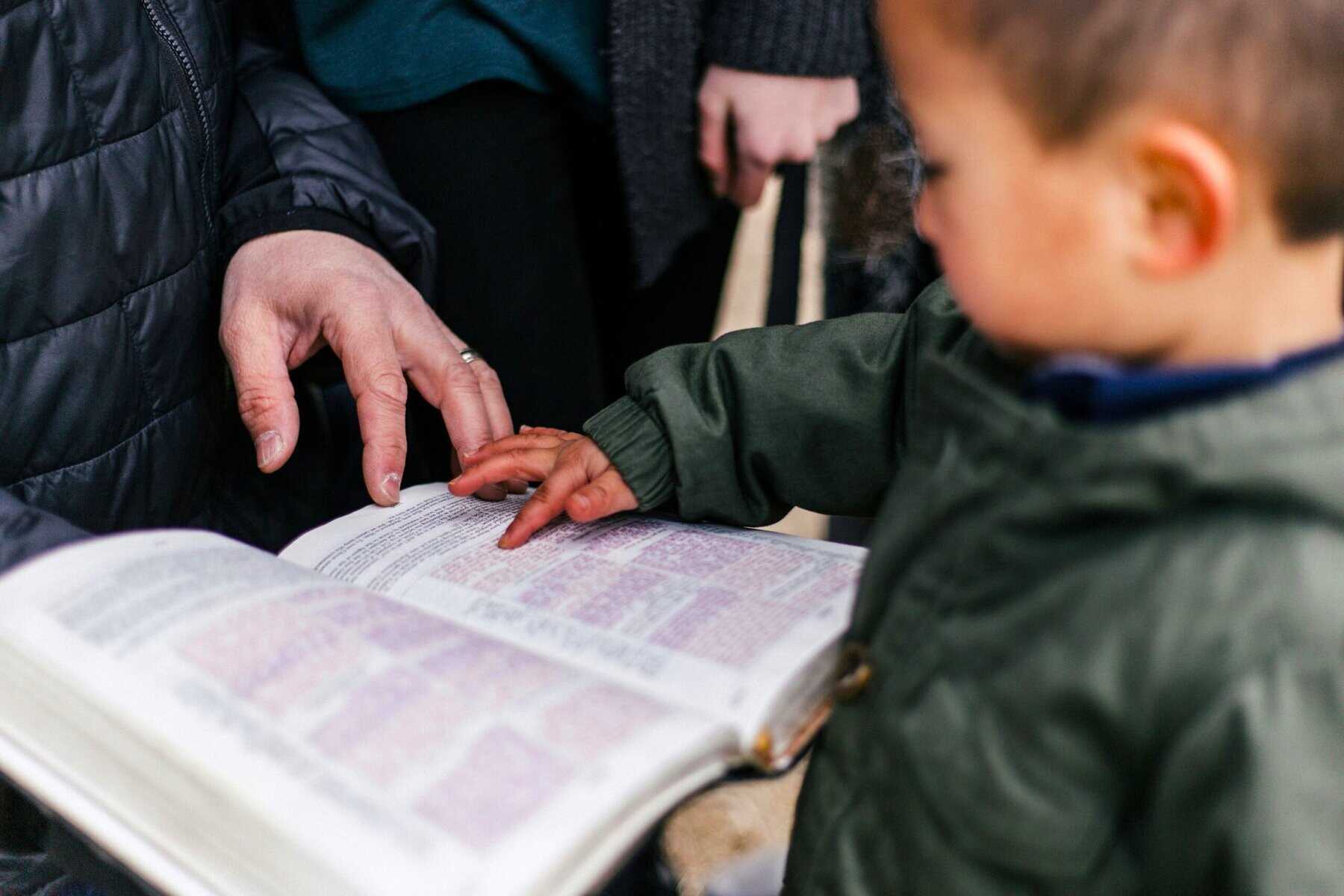 Adult guiding child’s hand while reading, showing how connection patterns form in the Family Environment.
