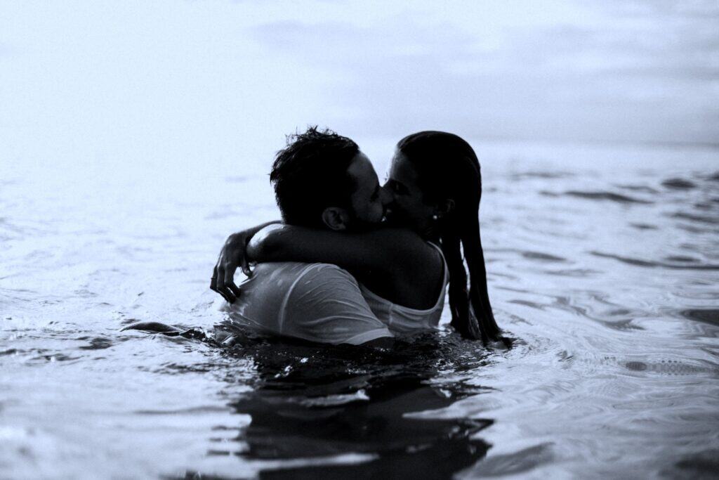 A close-up of a man and woman sharing a deep embrace in water, highlighting themes of love, trust, and emotional support. The serene water and gentle lighting evoke feelings of calmness and connection.