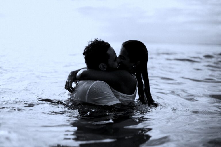 A close-up of a man and woman sharing a deep embrace in water, highlighting themes of love, trust, and emotional support. The serene water and gentle lighting evoke feelings of calmness and connection.