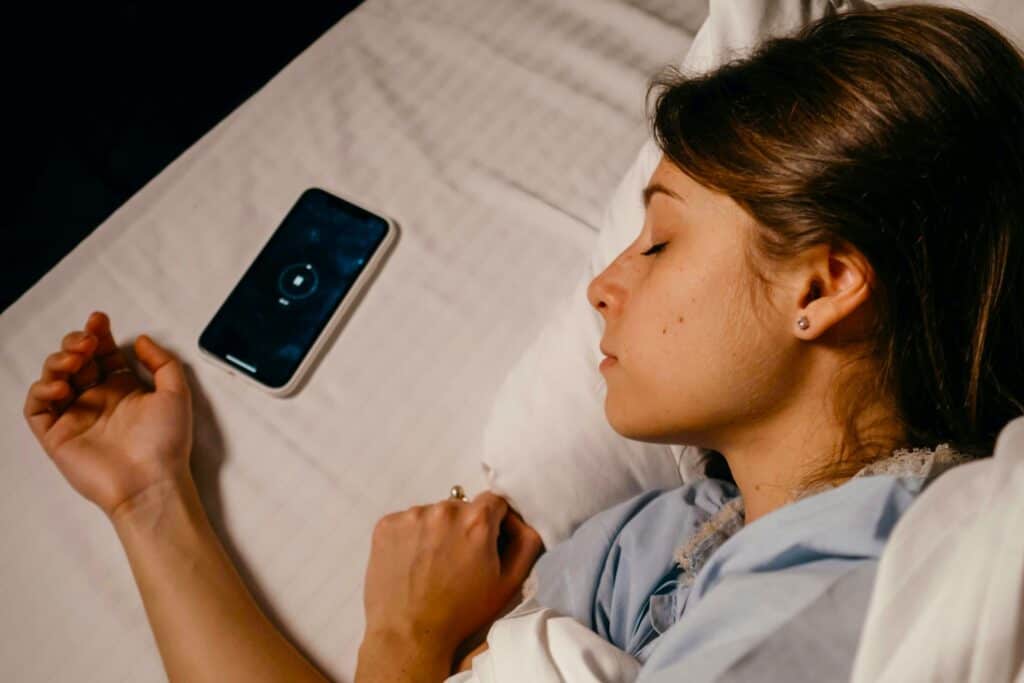 A woman resting peacefully beside her muted phone, symbolising Digital Habits Management and screentime control.