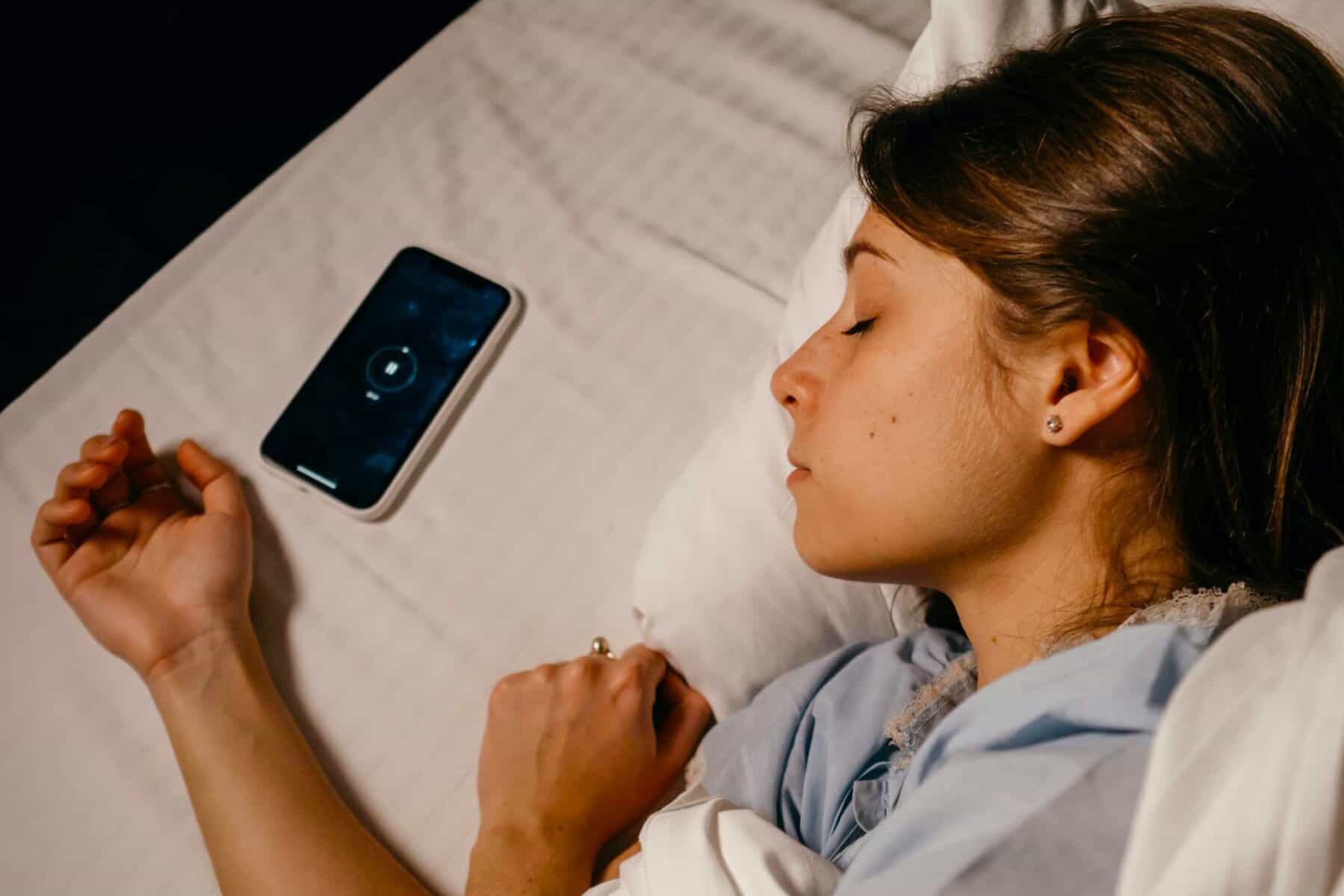 A woman resting peacefully beside her muted phone, symbolising Digital Habits Management and screentime control.