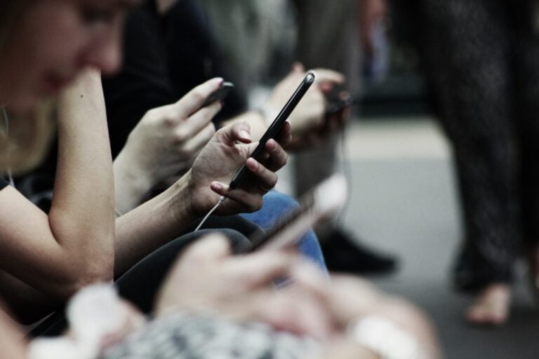 People scrolling on phones to escape boredom, reflecting modern distraction and lost time by Battling Boredom Behavior.
