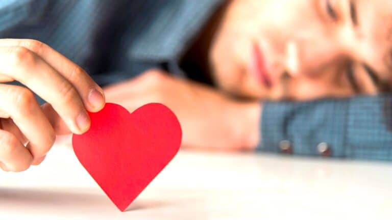 Person holding a red heart, showing stress from adverts shaping relationship dynamics and Valentine’s Day anxiety Commercialized Love.