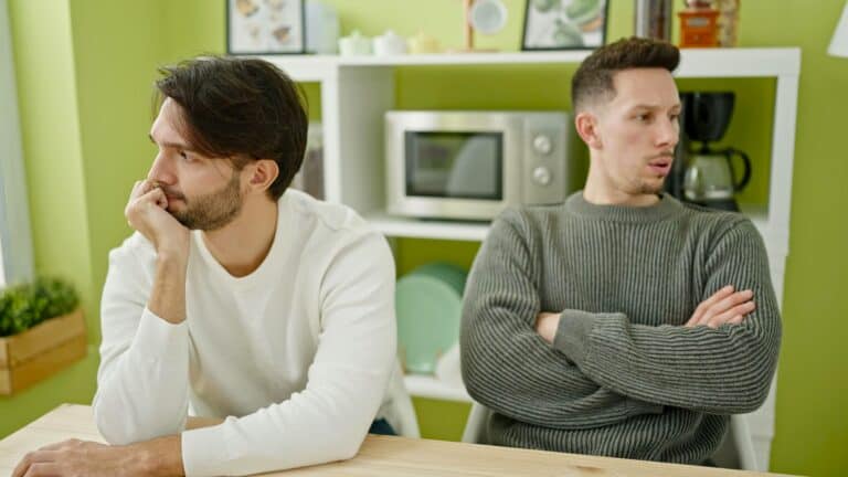 Couple sitting apart during emotional escalation showing communication attempts failing as emotions escalate quickly from Trauma and Conflict.