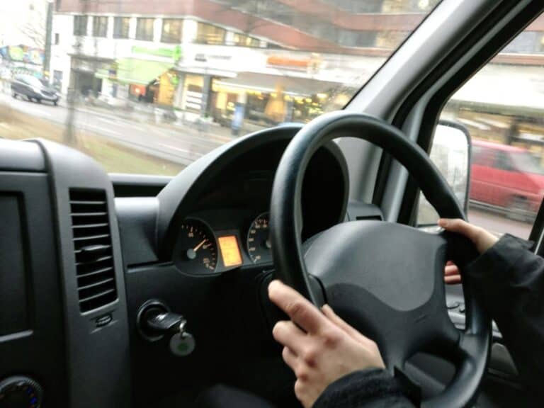 Older adult driving through city, showing difficulty adjusting to losing ability to drive and mood impact from Transport Independence Loss.