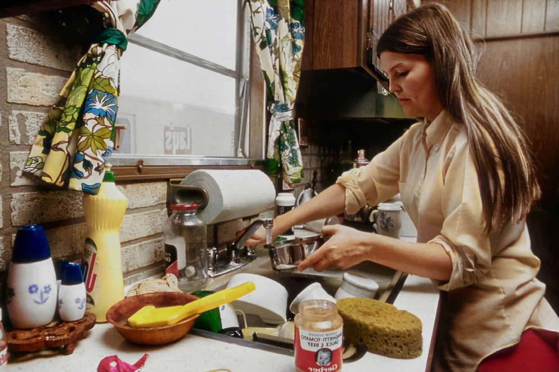 Woman washing dishes while managing invisible household planning, showing women’s mental load and Emotional Exhaustion in Mothers.