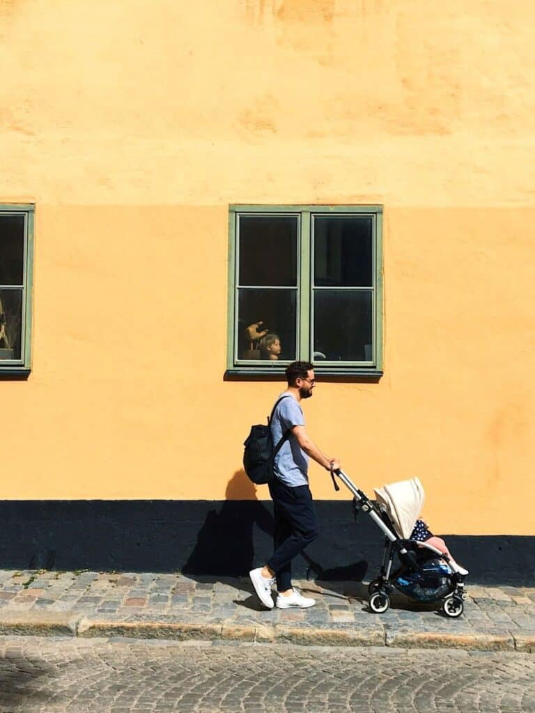 Father walking with stroller as child looks on, showing the circle of life and new chapters with Identity Shift in Parenthood.