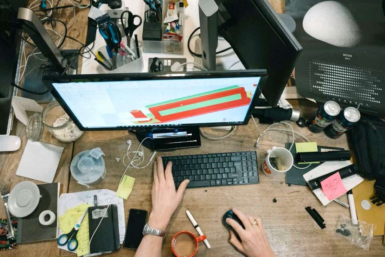 Cluttered workspace showing overworking to cope in certain moments, while work gives structure, triggering Anxiety-Driven Productivity Patterns.