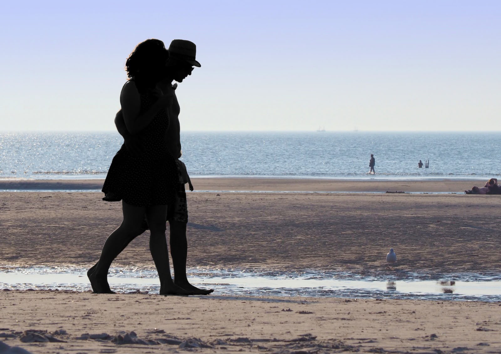 Silhouetted couple walking closely together on the beach during sunset, symbolising connection and emotional intimacy.